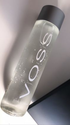 a water bottle with the word vasso on it hanging from a hook in front of a wall