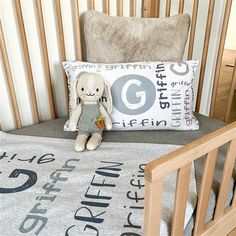 a stuffed animal sitting on top of a bed next to a pillow in a crib