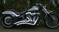 a black and silver motorcycle parked on the side of a road next to some trees