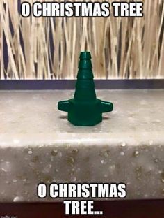 a green christmas tree sitting on top of a table next to a wall with the words o christmas tree