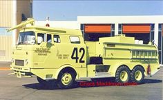 an old yellow fire truck is parked in front of a storage building with the number 42 on it's side