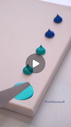 someone is using scissors to cut out circles on a piece of paper with blue and green paint