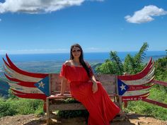 a woman in a red dress sitting on a bench with an american flag painted on it