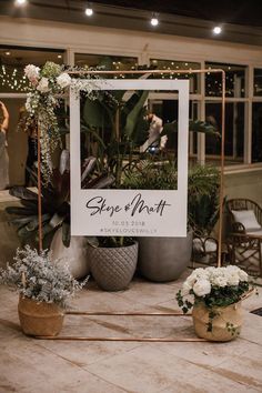 a sign that says sage and north sitting on top of a table with potted plants