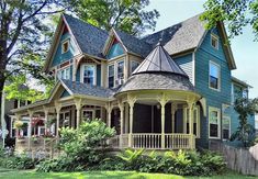 a large blue house sitting on top of a lush green field