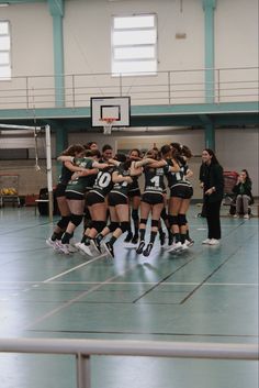 a group of young women standing next to each other on top of a basketball court