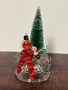 a small christmas tree and nutcracker in a glass bowl