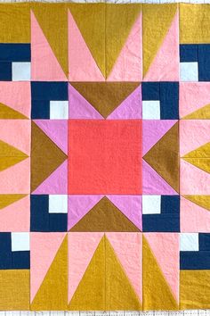 a pink, yellow and blue patchwork quilt with an orange center in the middle