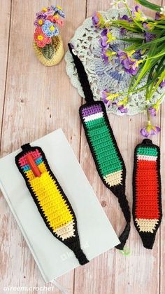 two crocheted book ends sitting on top of a table next to flowers and a lace doily