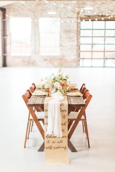 a table set with flowers and place settings for an outdoor wedding in the middle of a warehouse