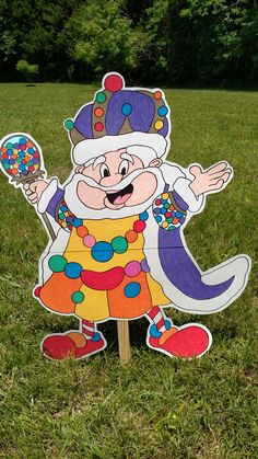 a cardboard clown standing on top of a lush green field