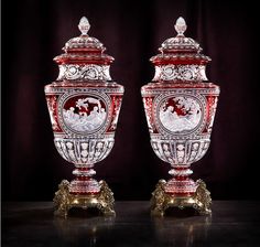 two red and white vases sitting next to each other on top of a table