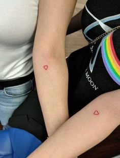 a woman with a rainbow tattoo on her left arm sitting in front of a chair