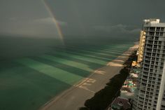 a rainbow is seen over the ocean in this view from a high rise apartment building