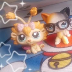 two little kittens wearing glasses on top of a bed with stars in the background