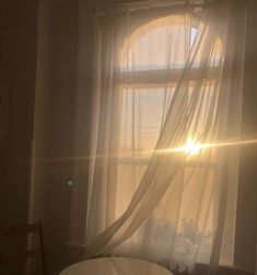 the sun shines brightly through curtains in a room with a round table and chair