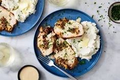 two blue plates topped with chicken, mashed potatoes and gravy next to a glass of milk