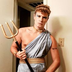 a man dressed in an ancient greek costume holding a sception and wearing a chain around his neck