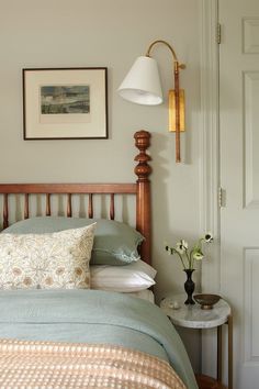 a bedroom with a bed, lamp and pictures on the wall above it's headboard