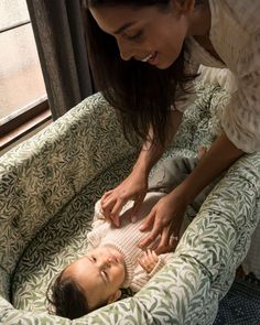 a woman is holding the arm of a baby in a green and white bedding