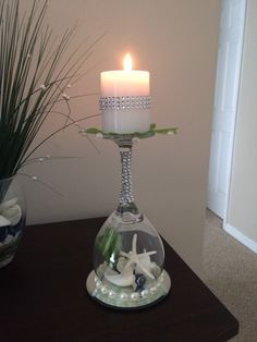 a candle that is on top of a glass vase with shells and starfish in it