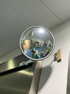 a mirror hanging from the side of an escalator shows a woman's reflection