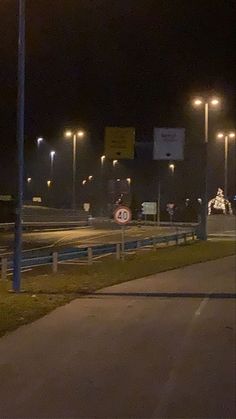 an empty road at night with street lights and signs on the side of the road