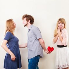 three people standing next to each other with hearts in their hands and one woman holding a red heart