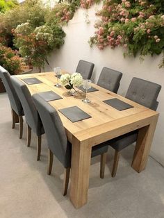 a wooden table surrounded by grey chairs and flowers