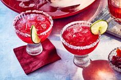 two red margaritas with lime slices and strawberries on the rim next to each other