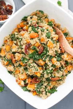 a white bowl filled with quinoa and carrots next to a wooden spoon