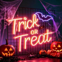 two pumpkins sitting in front of a neon trick or treat sign