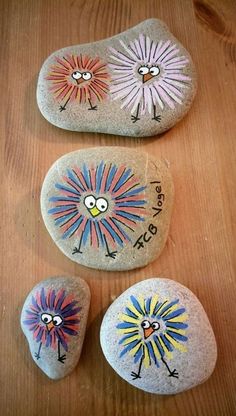 three painted rocks sitting on top of a wooden table