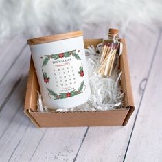 a cup and matches in a box on a white wooden surface with the calendar printed on it