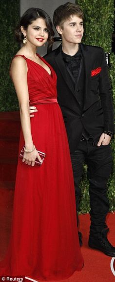 two people in formal wear standing on a red carpet