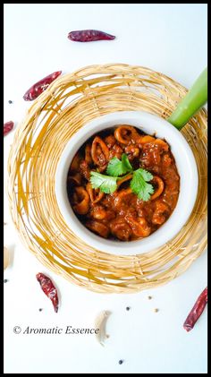 a white bowl filled with food on top of a wooden table next to red chili peppers