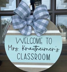 a welcome sign hanging on the front door of a classroom with a large blue bow