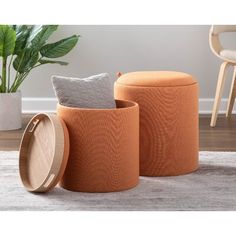 two orange stools sitting on top of a rug next to a potted plant