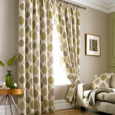 a living room filled with furniture and a window covered in green polka dot curtain panels