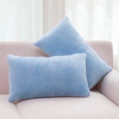 two blue pillows sitting on top of a white couch