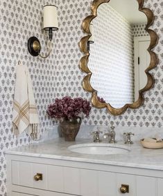 a bathroom with a sink, mirror and flowers on the counter in front of it