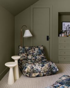 a living room with green walls and a floral couch in the corner next to a lamp