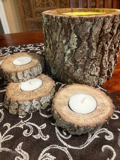 three candles are placed in front of a tree stump on a table with an intricate design