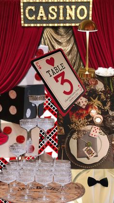 a table topped with lots of wine glasses next to a casino sign and other items