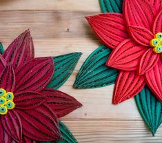 two red and green paper flowers on a wooden surface