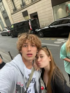 two young people standing next to each other on the street