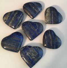 six blue heart shaped stones sitting on top of a white table next to each other