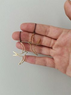 This is a gorgeous pair of swallow bird earrings.The birds face each other, when you wear them, but you can also wear them to look away from each other.They are outlines of swallow birds, of sterling silver,gold plated, hanging from small, sterling silver, oxidised hoops with silicon stops at the back.They are really beautifully made by our shop member, Dimitri.The birds are pictured in profile, while flying with open wings, one over the bird head and one underneath. The hoops and dangling birds Swallow Earrings, Birds Earrings, Swallow Birds, Bird Head, Open Wings, Swallow Bird, Bird Earrings, Black Earrings, Earrings Sterling Silver