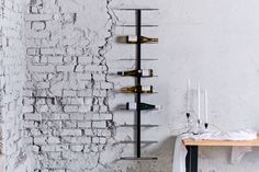 a wine rack on the wall next to a table with two candles and some bottles