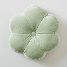 a green flower shaped pillow sitting on top of a white wall